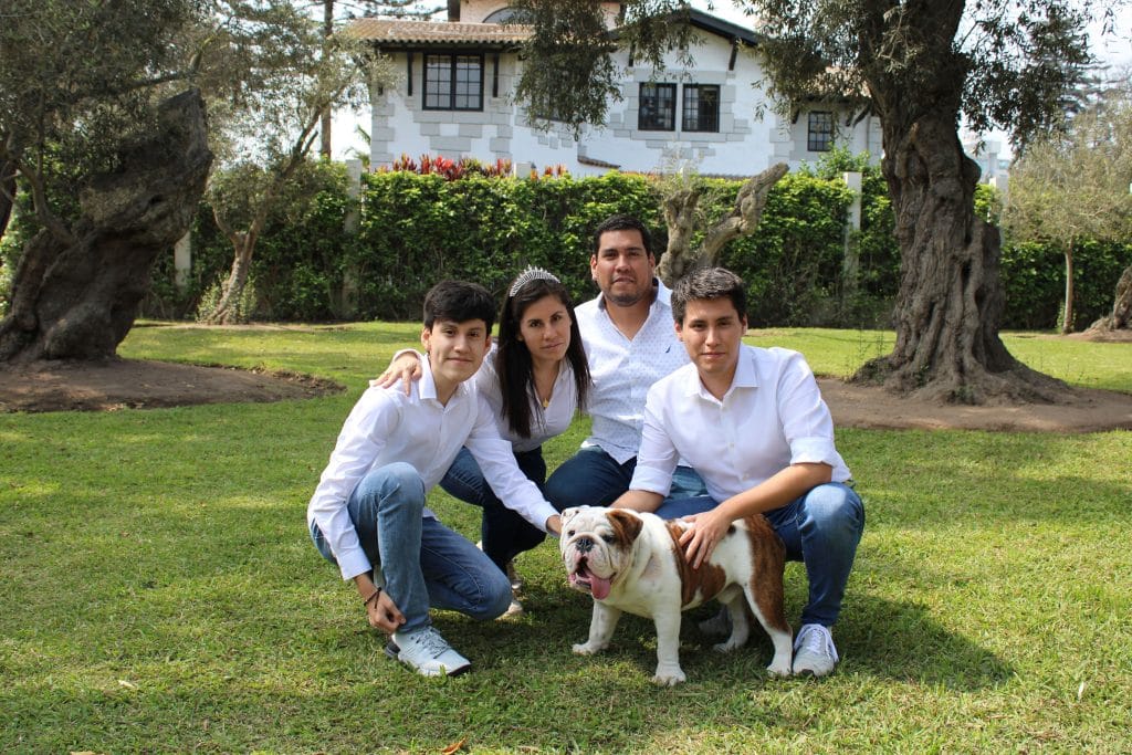 Nosotros A family posing with a bulldog in a sunny garden setting.
